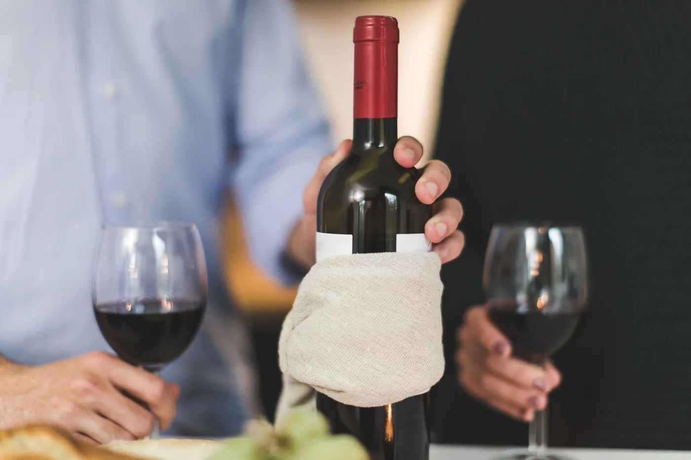 Two glasses of red wine being poured at a dinner table (representative photograph of a wine dinner, not Primuseum's own table)